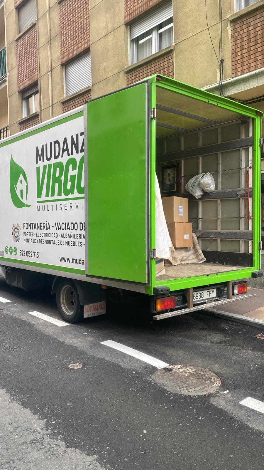 Lateral del camión de Mudanzas Virgos con la puerta trasera abierta y muebles protegidos listos para descargar